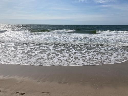 a beach with the ocean and footprints in the sand at Nordpalais vor Sylt in Emmelsbüll-Horsbüll