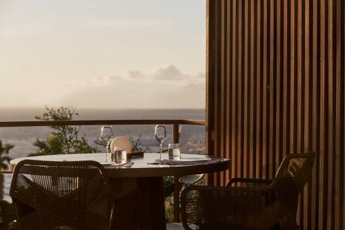 a table and chairs with wine glasses on a balcony at Mykonos Earth Suites in Mýkonos City