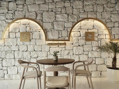a table and chairs in front of a stone wall at Mykonos Earth Suites in Mýkonos City