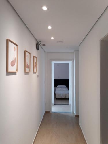 a hallway with a bed in a white room at Hotel Pousada Santa Maria in Aparecida