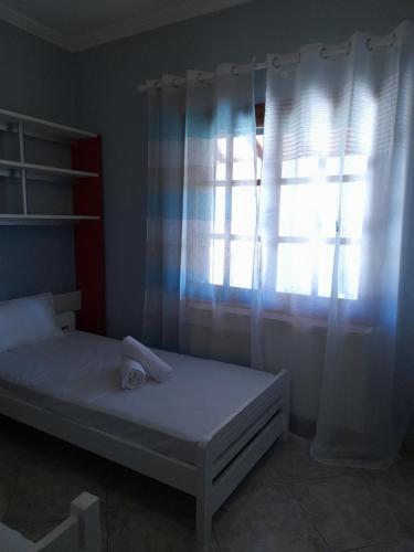 a bedroom with a bed and a window with curtains at Niki House in Ayios Nikolaos Sithonia
