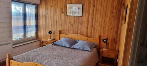 a bedroom with a bed with wooden walls and a window at La Rotonde des Grânes in La Bâtie-Neuve