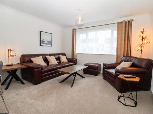 a living room with brown leather furniture and a window at 3 Granbrook Lane in Chipping Campden