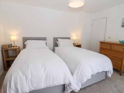 two beds in a bedroom with white sheets at 3 Granbrook Lane in Chipping Campden