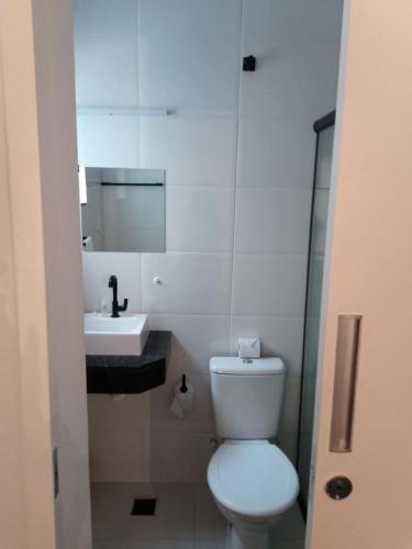 a white bathroom with a toilet and a sink at Hotel Pousada Santa Maria in Aparecida
