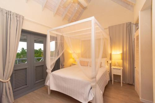 a bedroom with a canopy bed and a window at West Rock Villas in Saint James