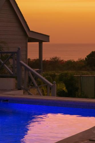 a swimming pool in front of a house with a sunset at West Rock Villas in Saint James