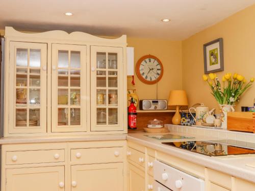 a kitchen with white cabinets and a clock on the wall at Little London in Battle