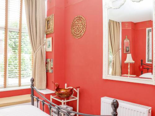a bedroom with red walls and a mirror at Little London in Battle