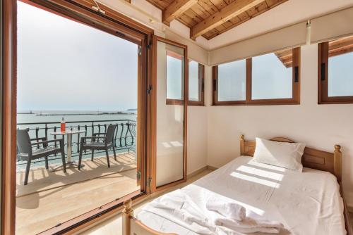 a bedroom with a bed and a balcony with a table at Saint Loukas Studios in Zakynthos