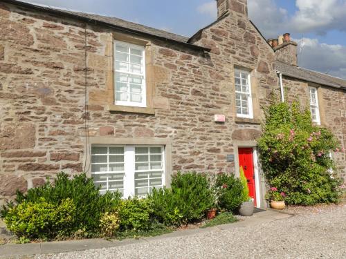 an old stone house with a red door at Greystones Cottage in Crieff