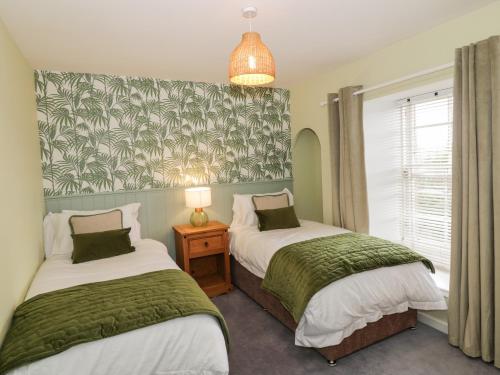 a bedroom with two beds with green and white sheets at Greystones Cottage in Crieff