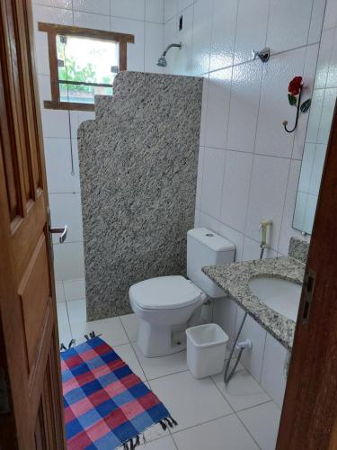 a bathroom with a white toilet and a sink at Pousada Mirante de Areia-Itaúnas in Itaúnas