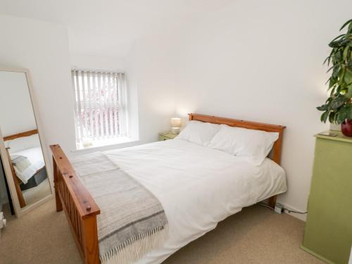 a bedroom with a bed with white sheets and a window at 4 Gerlan Road in Bangor