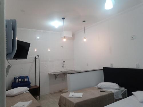 a room with two beds and a flat screen tv at Hotel Pousada Santa Maria in Aparecida