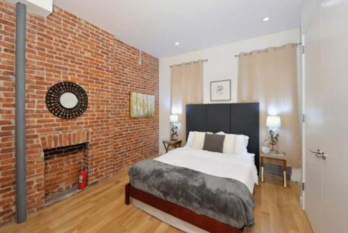Un dormitorio con una pared de ladrillo y una cama grande en Steps to Times Square Magnificent 2BR Apartment, en Nueva York