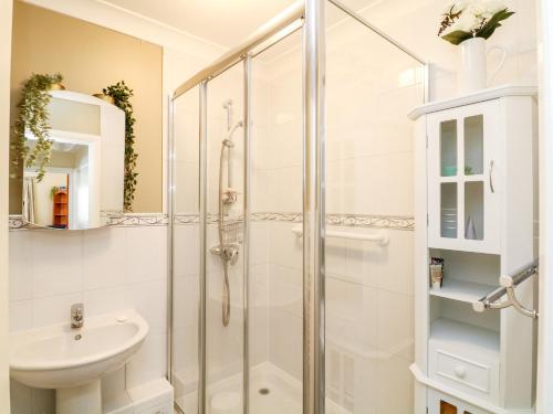 a white bathroom with a shower and a sink at 2 Chapelstones in Torquay
