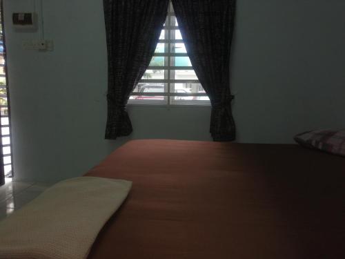 a bedroom with a bed and a window with curtains at Kamar Musafir MMS in Ipoh