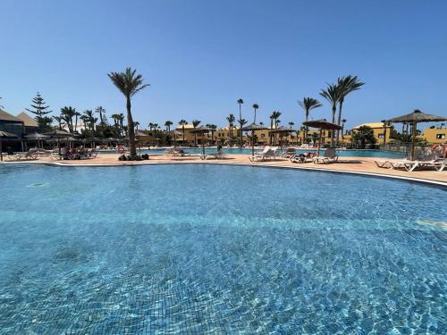 Una gran piscina en un complejo con palmeras. en Casa Julia - OASIS PAPAGAYO, en Corralejo