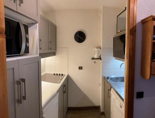 a small kitchen with a sink and a microwave at Ruim en modern appartement super centraal gelegen aan de piste in Valmorel