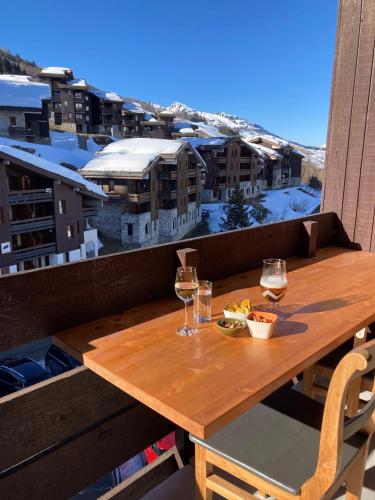 - une table en bois sur un balcon avec des verres de vin dans l'établissement Ruim en net appartement super centraal gelegen aan de piste, à Valmorel