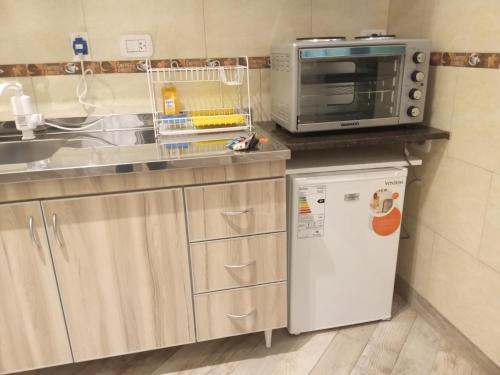 a small kitchen with a microwave and a refrigerator at Monoambientes in Villa Alsina