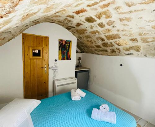 a bedroom with a blue bed with towels on it at Vecchia Casa sterna in Monemvasia