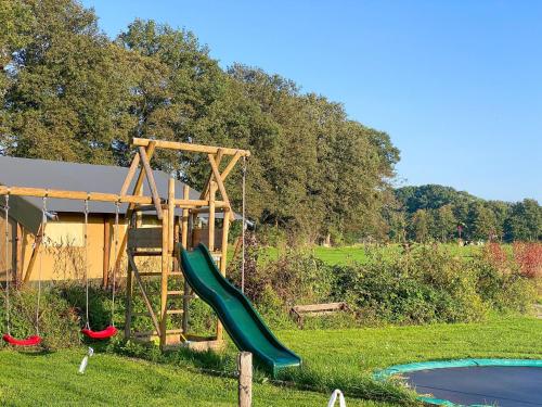 un parque infantil con un tobogán verde en un campo en camping?glamping morskersweitje en Winterswijk