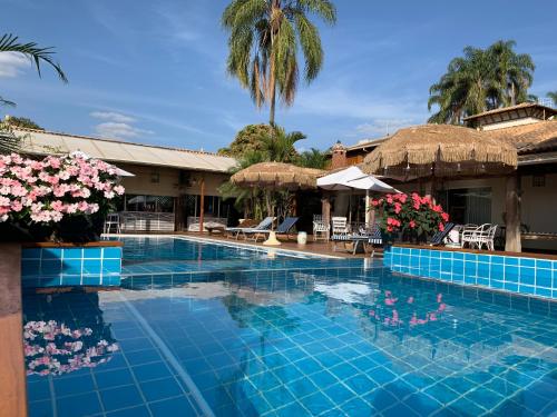 una piscina in un resort con fiori e ombrelloni di Villa Maria Pousada de Charme a Brotas