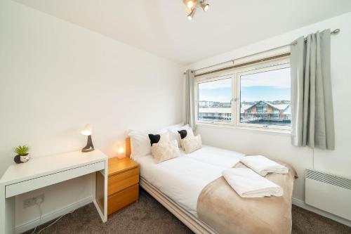 a bedroom with a bed with a desk and a window at Quayside Apartment in Dundee