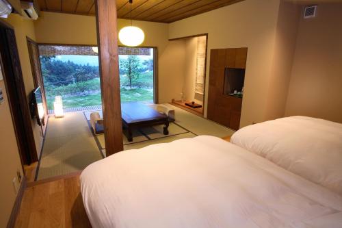 a bedroom with two beds and a table and a window at Ryokan Konomama in Minami Aso