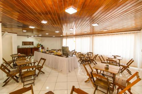 a room with wooden ceilings and tables and chairs at Na Praia Hotel in Porto Seguro