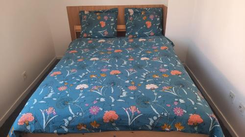 a bed with a blue bedspread with flowers on it at Maison en Location Fresnes sur Marne in Fresnes-sur-Marne