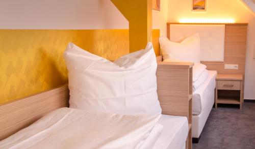two beds in a room with white pillows at Alpha & Omega Hotel in Stuttgart