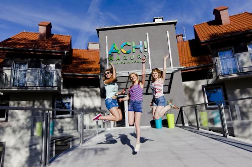 two girls jumping on a balcony in front of a building at Ach Mazury in Mikołajki