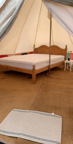 a bed in a tent with a rug on the floor at Bell tent 3 Glyncoch isaf farm in Llwyn-Dafydd