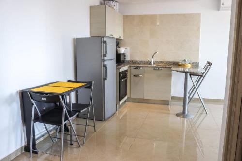 een keuken met een koelkast en een tafel en stoelen bij Coin Du Ciel-Vue Imprenable Océan avec piscine in Agadir
