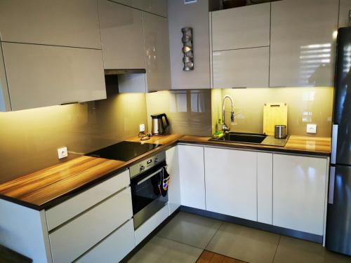 a kitchen with white cabinets and a sink and a stove at Apartament Kraków Arena 20B in Krakow