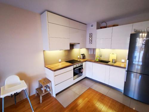 a kitchen with white cabinets and a black refrigerator at Apartament Kraków Arena 20B in Krakow