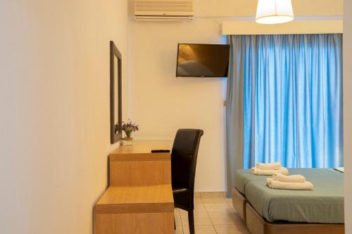 um quarto com uma secretária, uma cama e uma secretária com uma cadeira. em OCEANA Beach Hotel em Paralia Panteleimonos