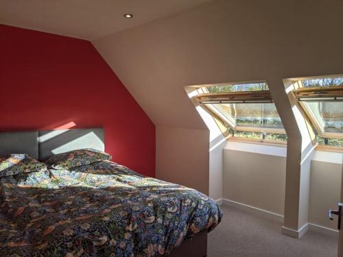 a bedroom with two windows and a bed in it at Willowbarn Rafford Self Catering in Forres