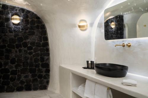 a bathroom with a black sink and a mirror at Alme Luxury Cave Villas in Vóthon