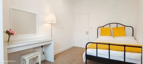 a bedroom with a bed with yellow pillows at Phlox Garden in Sutton