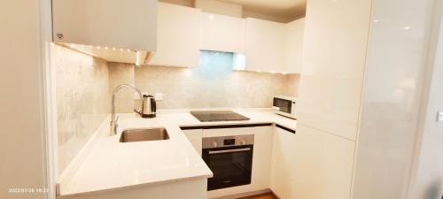 a white kitchen with a sink and a stove at Phlox Garden in Sutton