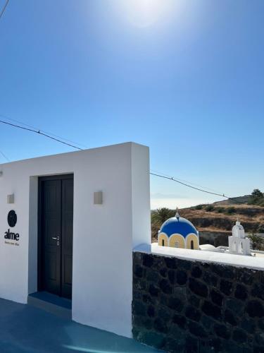 a white building with a black door and a dome at Alme Luxury Cave Villas in Vóthon
