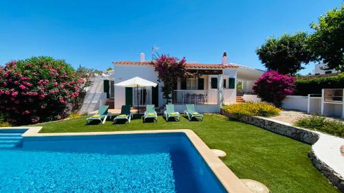 un patio trasero con piscina y una casa en Villa Cristina, en Binibeca
