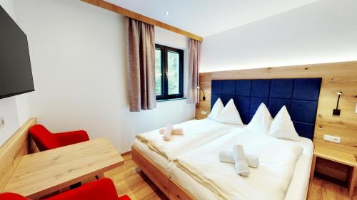 a bedroom with a large bed and a red chair at Pension Lederergütl - Jokercard & Parkplatz inkl in Saalbach Hinterglemm