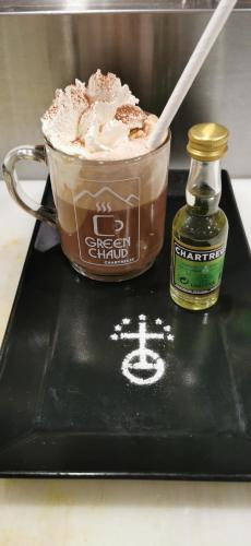 a black tray with a chocolate shake and a bottle of syrup at Hôtel Au Feu De Bois in Autrans