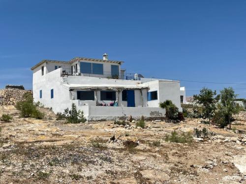 une maison blanche au milieu d'un champ dans l'établissement Dar Nouha : un appartement sur l'océan, à Wassane