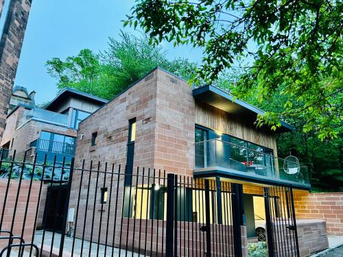 a brick house with a fence in front of it at DESIGNER HOUSE - University of Glasgow / Central Glasgow 'Hillhead' West End G12 - Luxurious & Contemporary Detached House / Terrace / Garden / 'electric car charging' Garage Parking in Glasgow